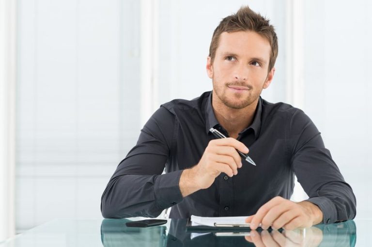 19500096 young businessman thinking and wondering while writing a paper